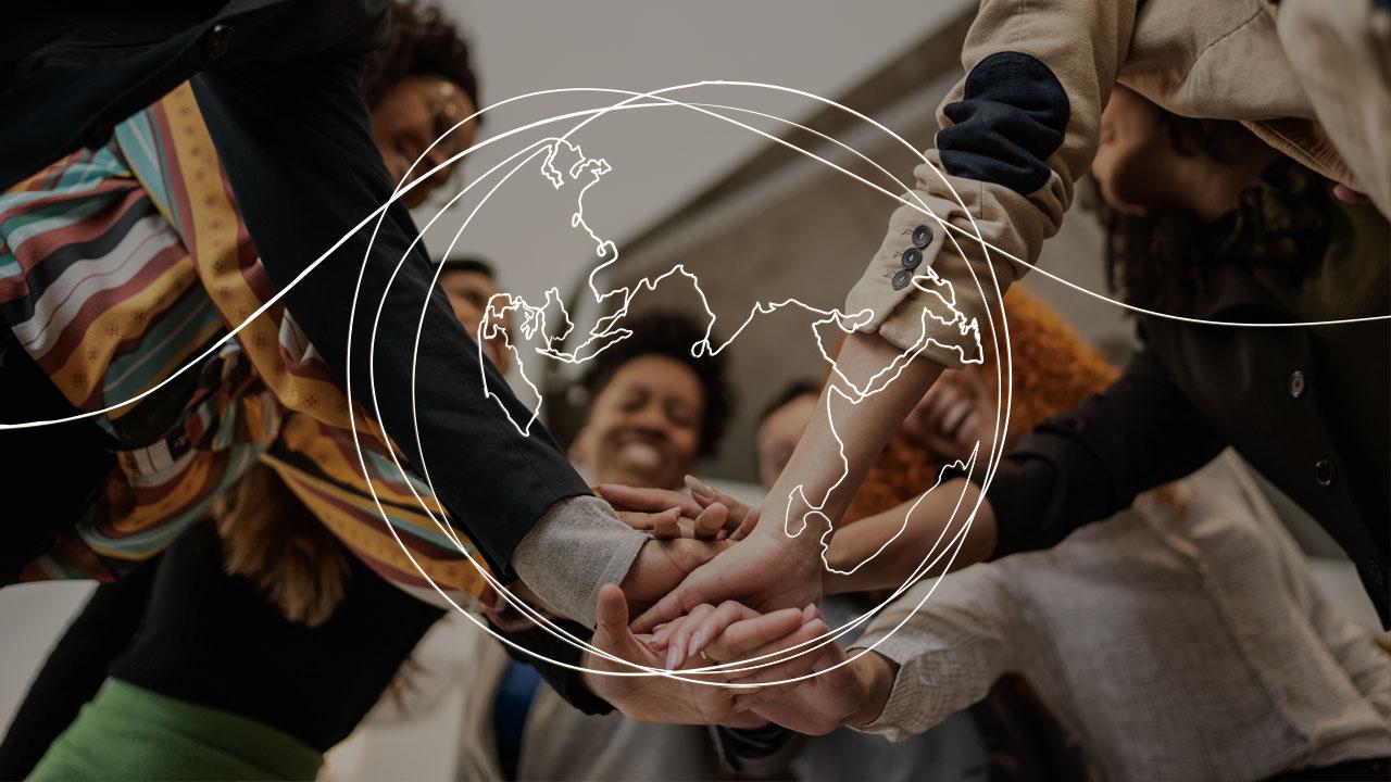 A line drawing of a global over a photo of a diverse group of people with their hands in the middle of the group in a hand stack